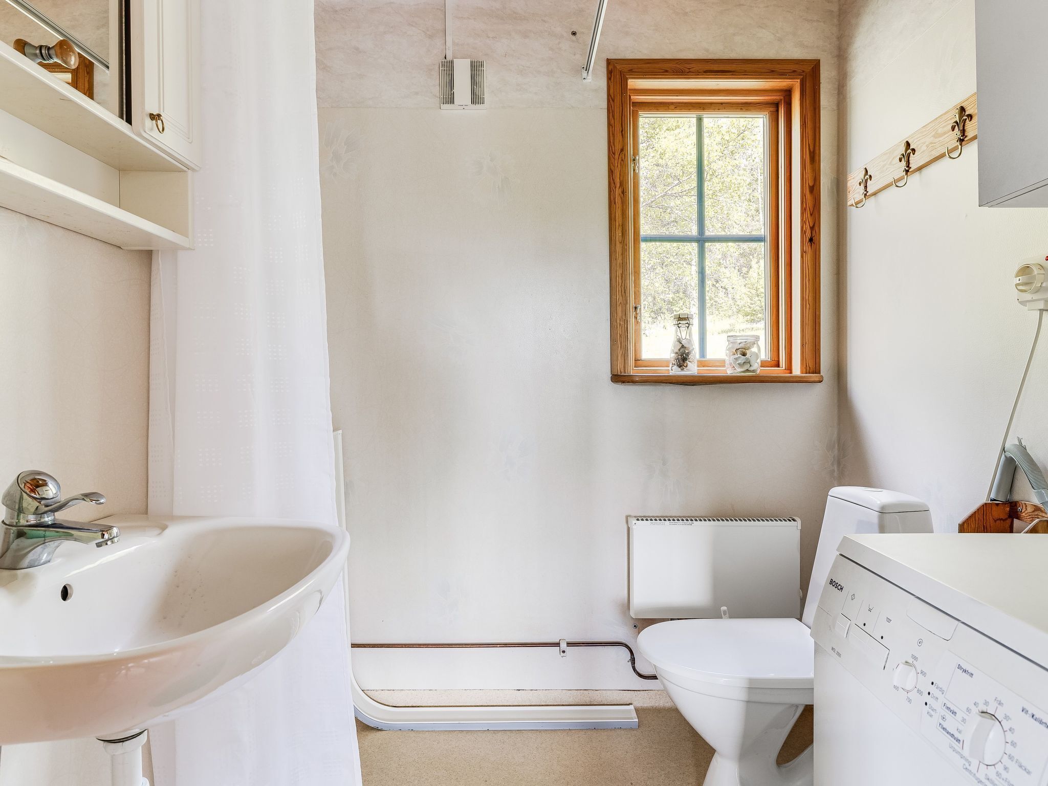 A bathroom with a white sink, toilet, and window.