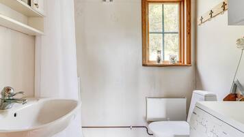 A bathroom with a white sink, toilet, and window.