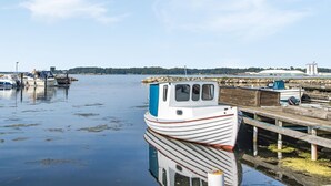 A small boat docked at a pier with calm water and a clear sky.