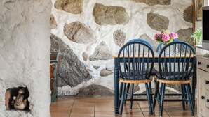 A dining area with a stone wall, wooden ceiling, and blue chairs.