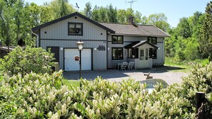 Una casa a due piani con garage, portico e un piccolo giardino.