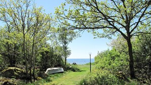 Area naturale all'aperto con tavolo da picnic e lampione, circondata da alberi e vista sul mare.