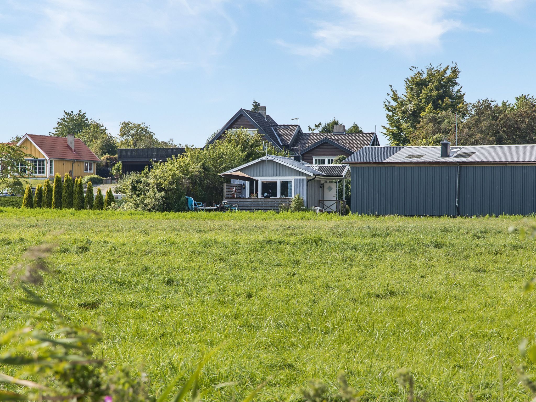 Ett bostadsområde med hus, en gräsyta och ett metallskjul.