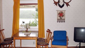 Un'area pranzo con un tavolo di legno, quattro sedie, un divano blu e una televisione.