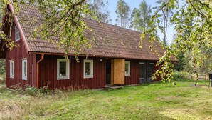 En rød træbygning med tegltag, en trædør og vinduer.