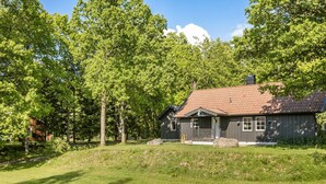 A rustic cabin with a sloped roof, surrounded by lush greenery and trees. - Ängasjö by Interhome (Östra Frölunda)