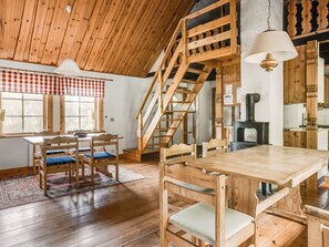 Un interior de madera con una mesa de comedor, sillas, una escalera y una chimenea.