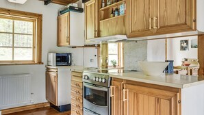 A kitchen with wooden cabinets, a stove, oven, microwave, and a window. - Ängasjö by Interhome (Östra Frölunda)