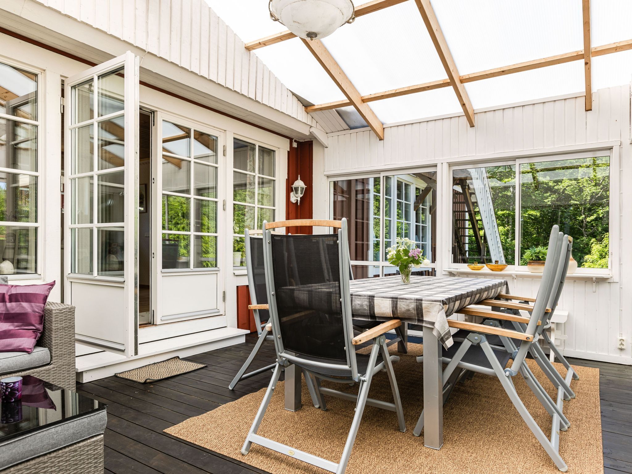 Une terrasse extérieure avec une table et des chaises, une pergola et une vue sur la verdure.