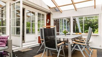 Une terrasse extérieure avec une table et des chaises, une pergola et une vue sur la verdure.