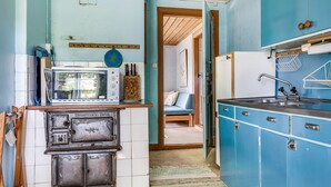 Une cuisine de taille réduite, équipée d’une cuisinière, d’un four à micro-ondes, d’un évier et de meubles de rangement bleus.