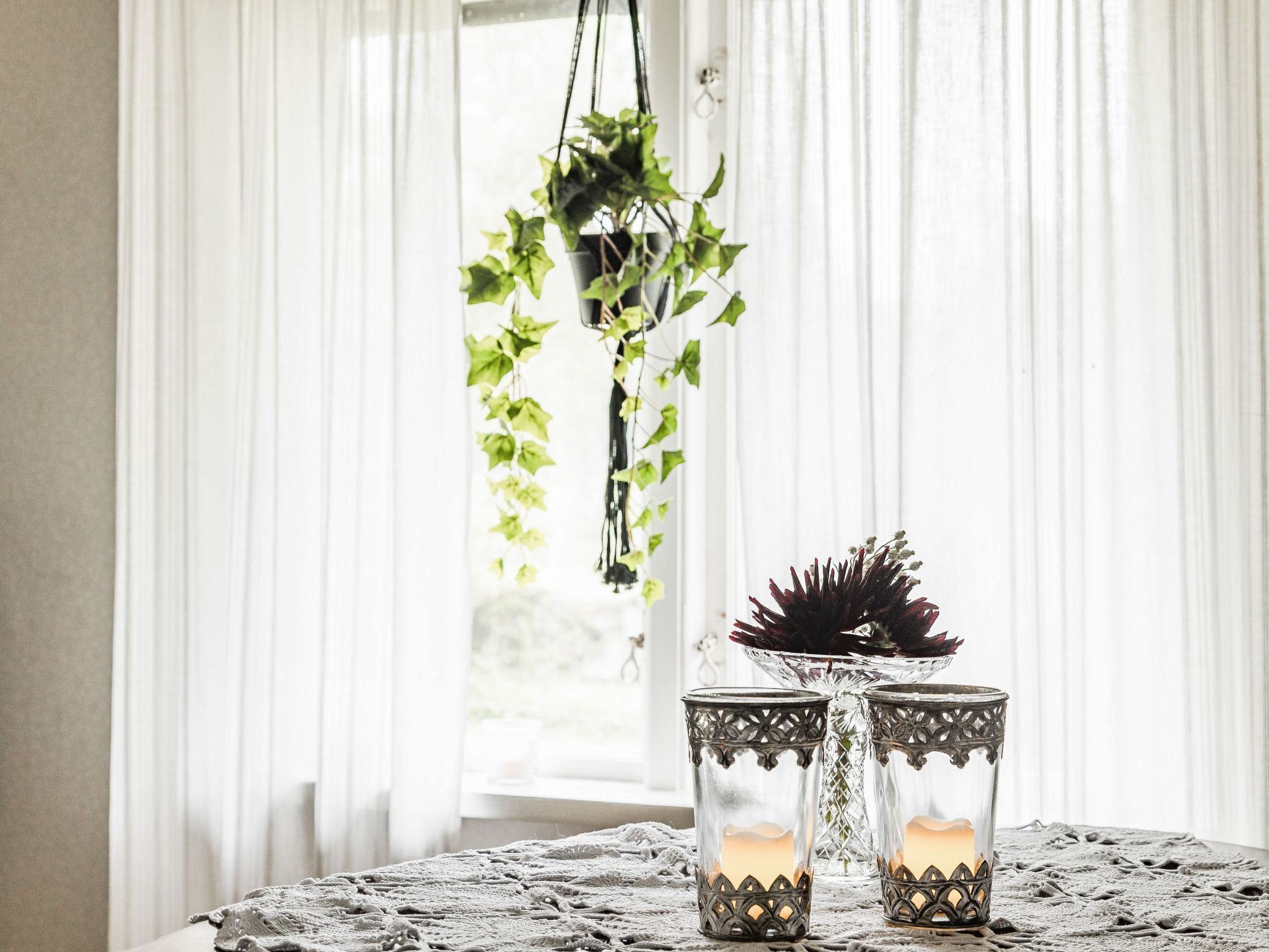Een tafel met twee kandelaars en een hangplant.