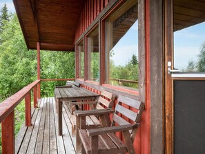 A wooden deck with benches and a view of a forested area.