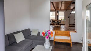 A modern living room with a gray sofa, a wooden bench, and a vase of colorful flowers.