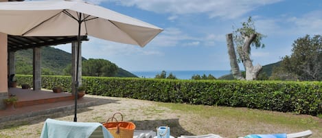 An outdoor seating area with two lounge chairs, a table, and a large umbrella.