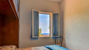 Une chambre à coucher avec un lit, une fenêtre avec des rideaux et une vue sur la mer.