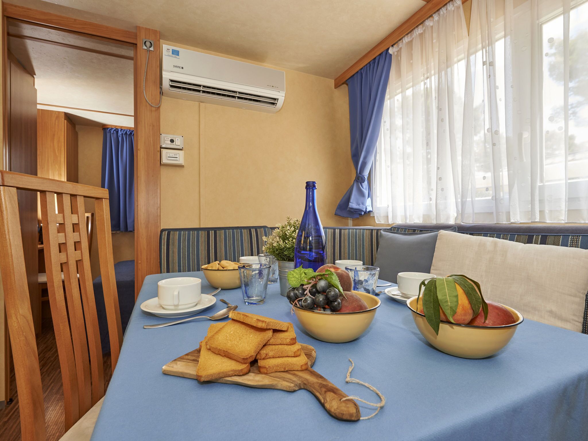 Un coin repas avec une table mise pour le petit-déjeuner, comprenant du pain, des fruits et des boissons.