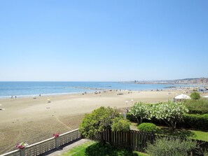 Ein Strand mit blauem Himmel, sandigem Ufer und einer fernen Stadtansicht.
