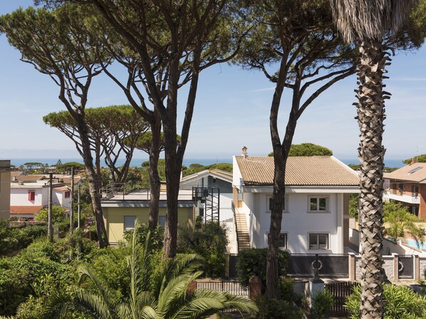 A residential area with houses, trees, and a view of the sea.