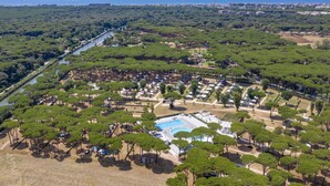 Vista aérea de um resort com piscina, cercado por vegetação densa e um rio.