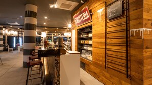 Uma área de bar com uma placa que diz "BRUTERIA" e uma lousa acima.