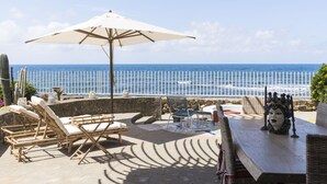 A seaside patio with lounge chairs, a table, and an umbrella. - La Califfa by Interhome (Santa Marinella)