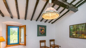 Ein Schlafzimmer mit Bett, einem Fenster mit Blick auf einen Weinberg, einem Gemälde und einer Chandelüster.