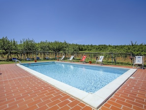 A rectangular pool with a brick deck, surrounded by lounge chairs and a vineyard in the background. - Fattoria Petraglia - Cedro by Interhome (Monteriggioni)