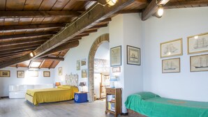 A room with wooden beams, two beds, a desk, and framed pictures on the walls.
