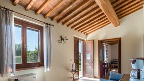 A room with a wooden ceiling, a dining table, a blue sofa, and a coffee machine. - Terrazza by Interhome (Istia d'Ombrone)