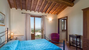 A bedroom with a bed, a chair, a small table, and a view of the outdoors. - Terrazza by Interhome (Istia d'Ombrone)