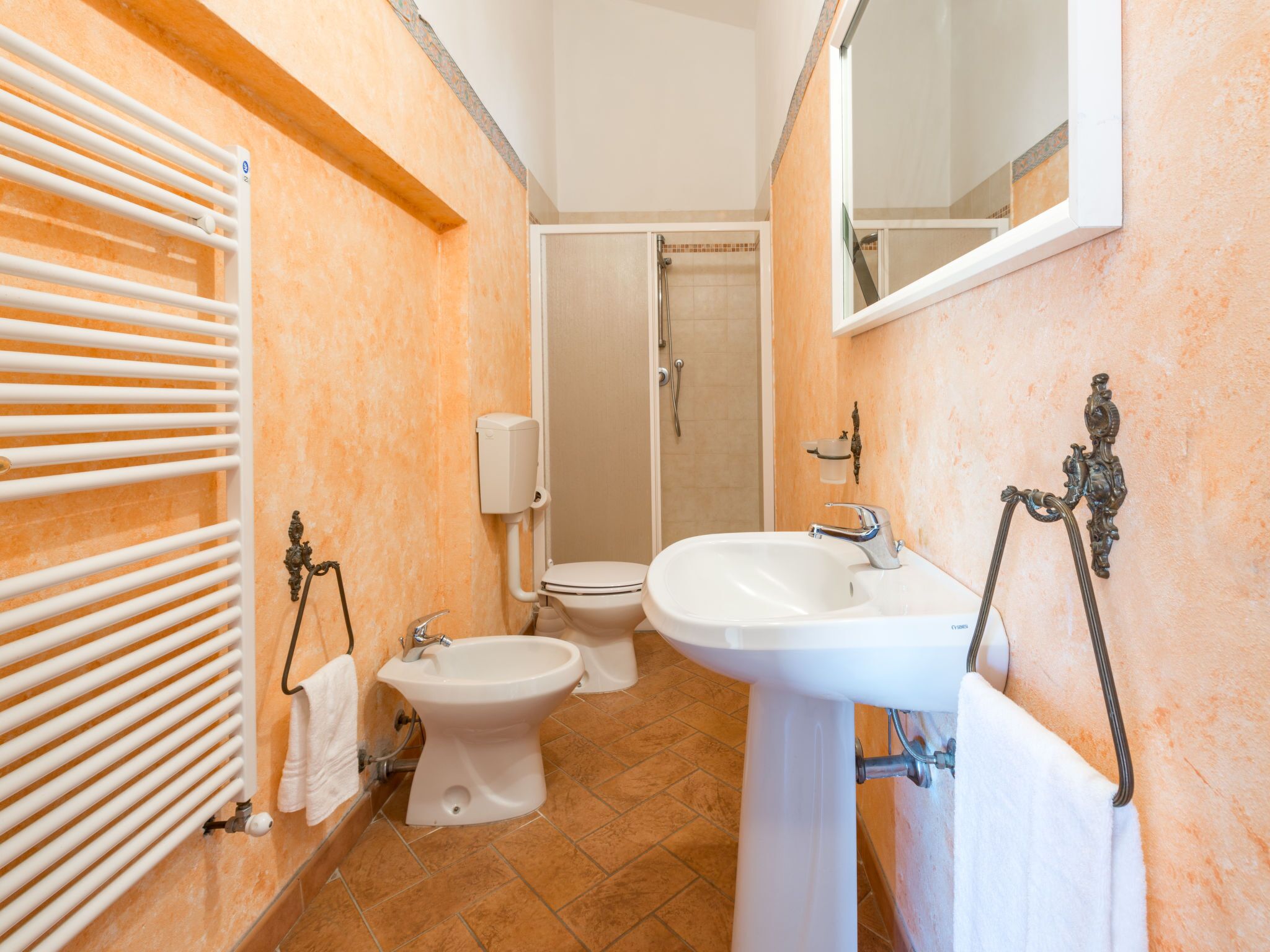 A bathroom with a toilet, bidet, sink, and shower.