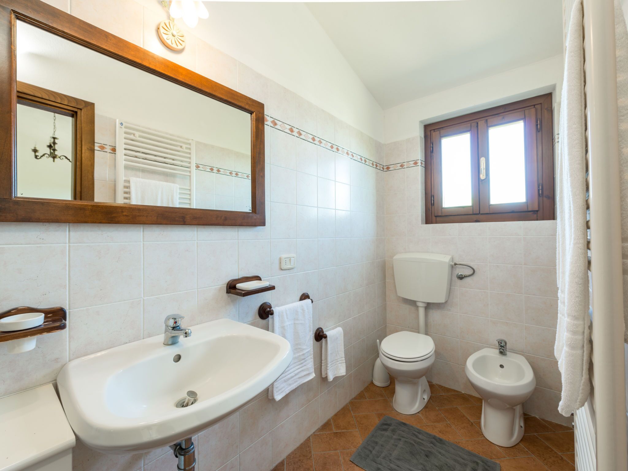 Ein Badezimmer mit Waschbecken, Toilette, Bidet und Fenster.