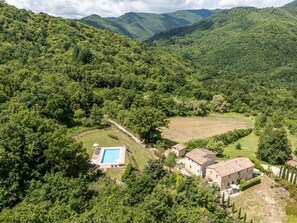 A villa with a swimming pool surrounded by lush greenery and hills. - Apartment Arco by Interhome (Travale)
