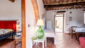 A room with a bed, a table, a lamp, and a chair. There is a door leading to an outdoor area with a table and chairs. - Apartment Arco by Interhome (Travale)