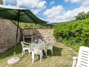 An outdoor patio with a stone wall, a table with chairs, and a green umbrella. - Il Forno by Interhome (Travale)
