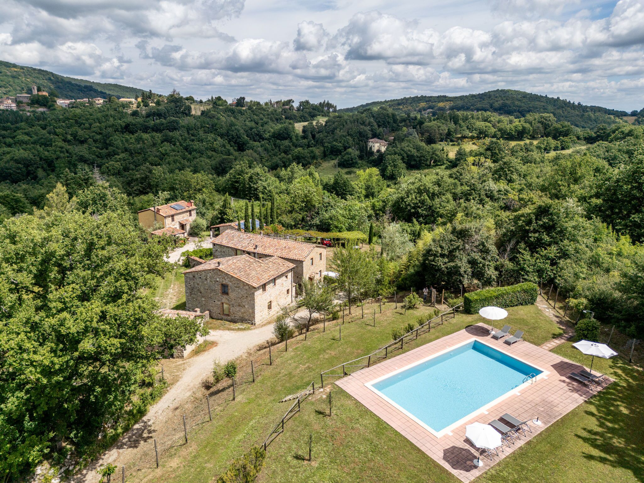 A villa with a swimming pool, surrounded by lush greenery and hills.