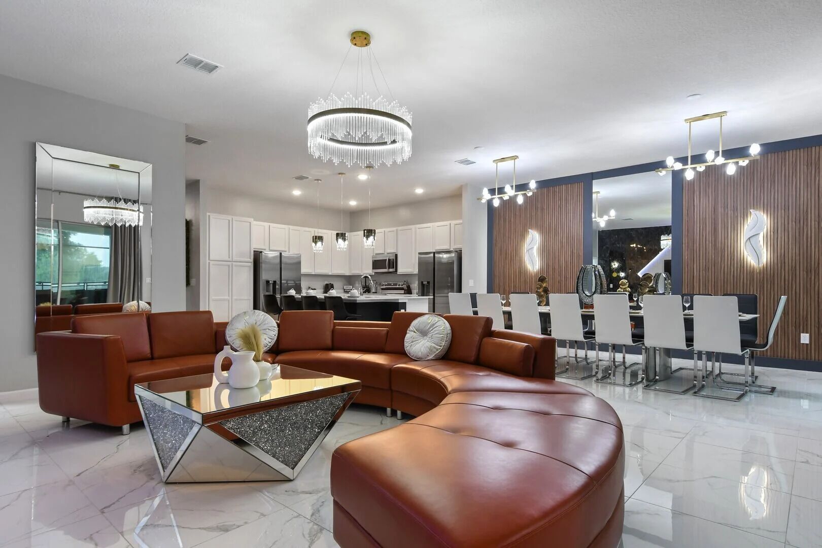 Un salon moderne avec un canapé d’angle, une table basse en verre et un coin repas doté d’un bar.