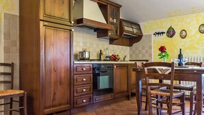 Eine Küche mit Holzausstattung, einem Herd und einem Essbereich mit Stühlen und einem Tisch.