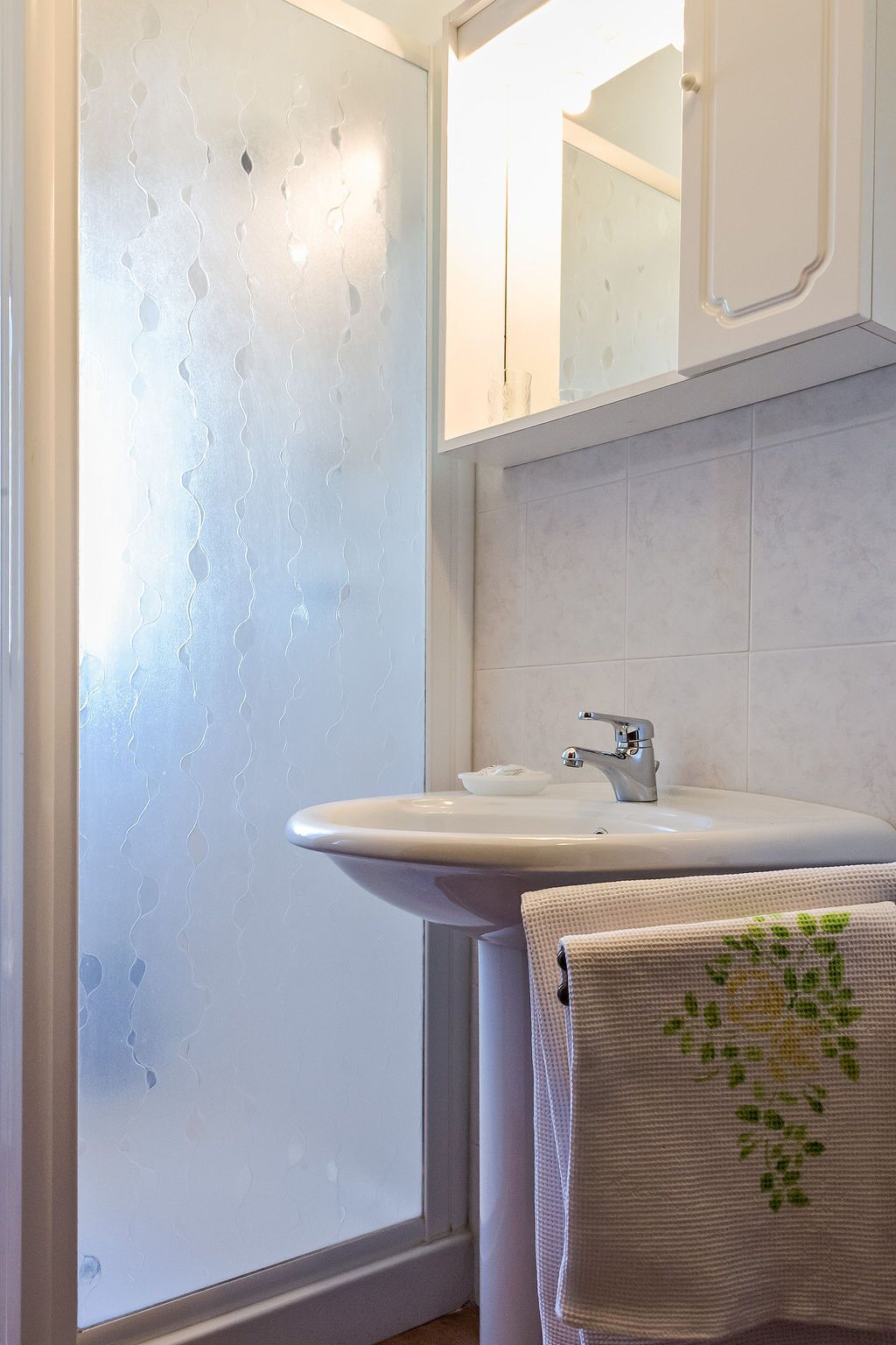 A bathroom with a white sink, a towel rack with a towel, and a mirror above the sink.