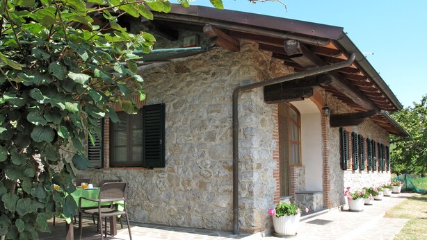 A stone building with a covered patio, outdoor seating, and potted plants. - Villetta degli Orti by Interhome (Gombitelli)