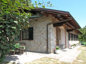 A stone building with a covered patio, outdoor seating, and potted plants.