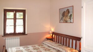 A bedroom with a bed, a window, a bedside table with a lamp, and a framed picture on the wall. - Villetta degli Orti by Interhome (Gombitelli)