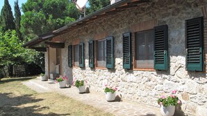 A stone building with green shutters, a satellite dish, and potted flowers along the pathway. - Villetta degli Orti by Interhome (Gombitelli)