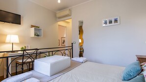 A hotel room with a bed, a desk, a chair, a small table, a lamp, and a wall-mounted TV. - La Rondine by Interhome (San Giuliano Terme)