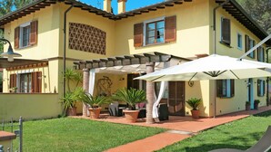A two-story house with a patio area, outdoor furniture, and potted plants. - La Rondine by Interhome (San Giuliano Terme)