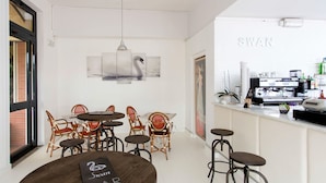 A modern bar with round tables and wicker chairs, a coffee machine, and a large window. - Apartment Italia by Interhome (Bocca di Magra)