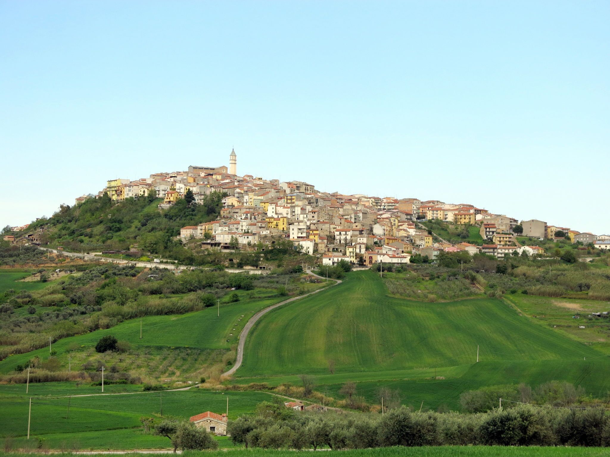 A hillside town with a prominent tower, terraced houses, and green fields.