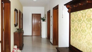 Un passadís amb portes de fusta, una paret blanca i un paper pintat amb motius al costat dret.