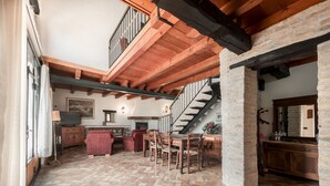 A spacious living area with a herringbone-patterned floor, wooden furniture, a fireplace, and a staircase leading to an upper level. - Domus Magna by Interhome (Povoletto)